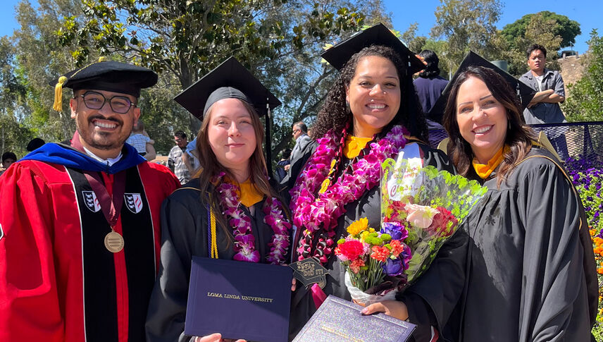 smiling graduates in regalia holding diplomas